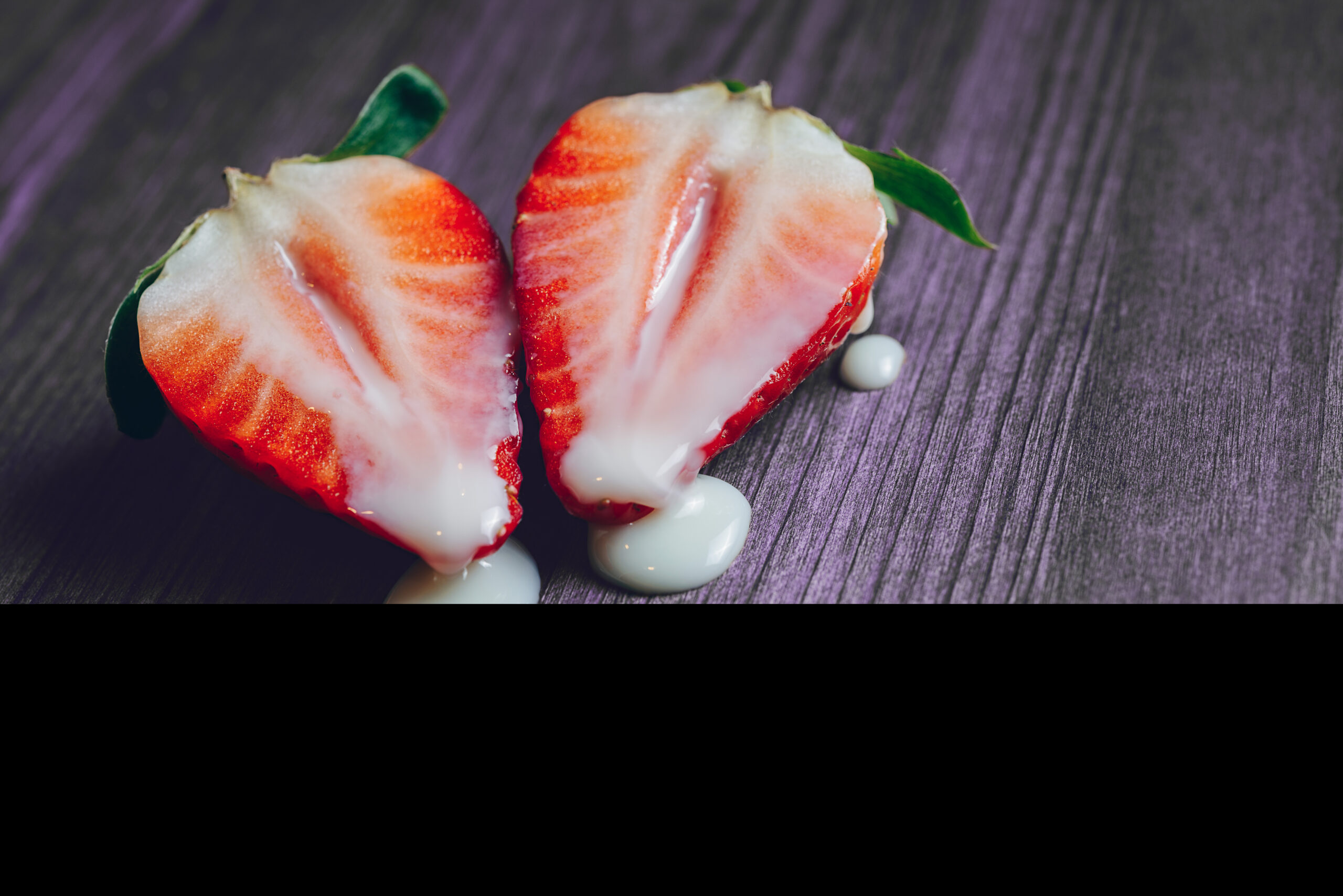 metaphor of sex with strawberries and milk in a purple wooden background. Vagina and semen symbol, sex concept. Copy space for text